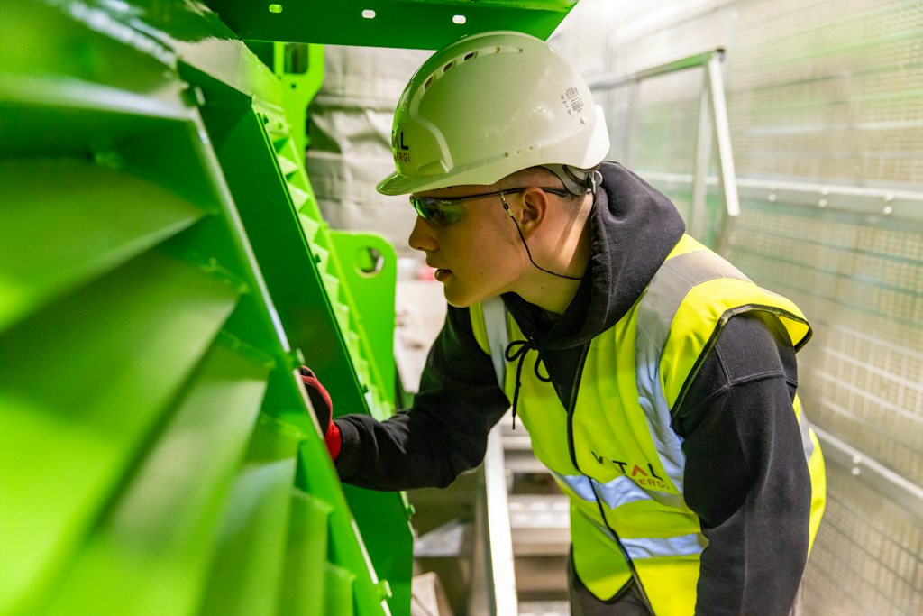 Technician in safety gear inspecting equipment