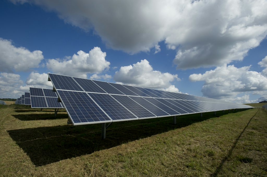 Solar panels in a field under a cloudy sky